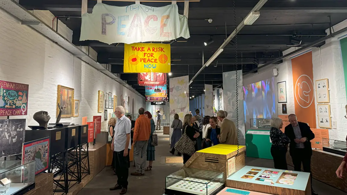 People walk around the exhibits including peace banners and posters