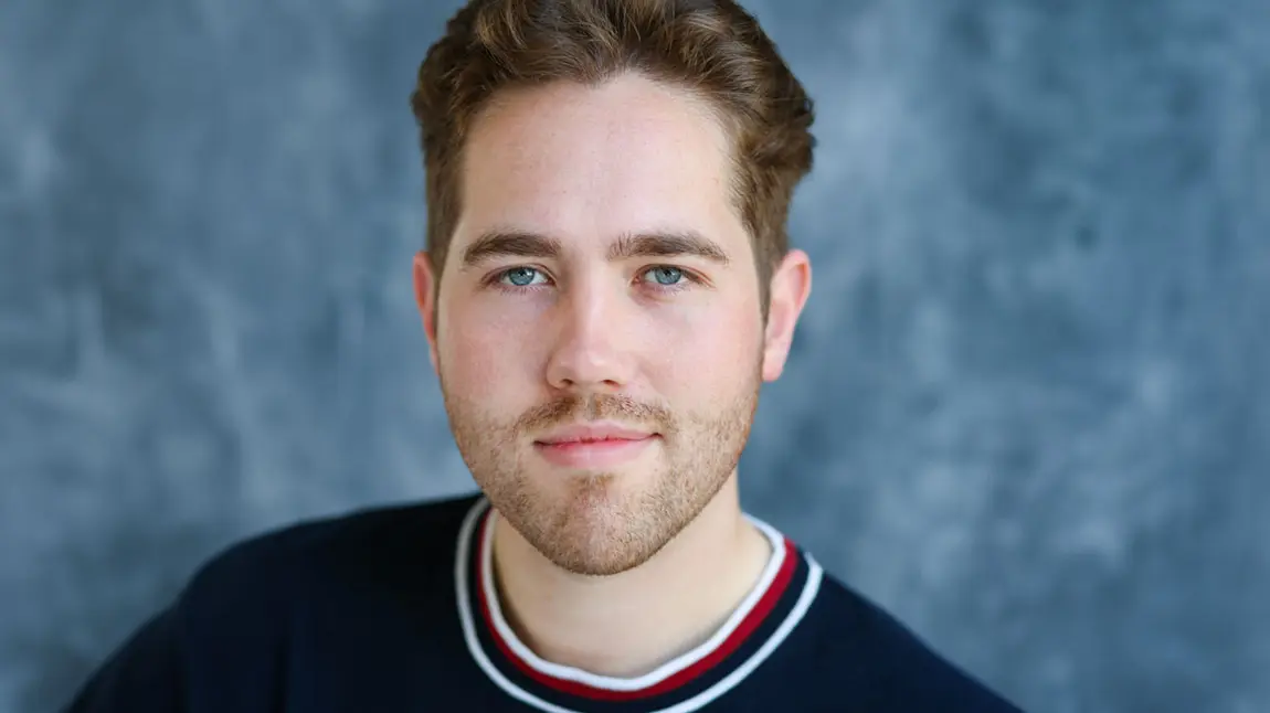 A studio portrait of a man with short brown hair