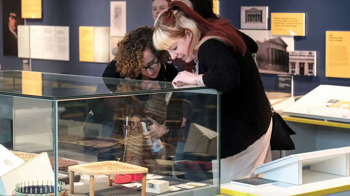 Two women looking into a glass museum display case.