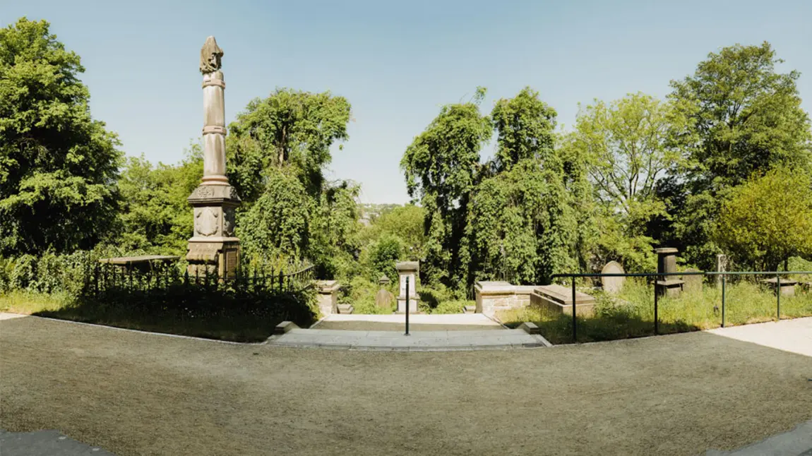 A view from the top of the cemetery overlooking grave stones and trees