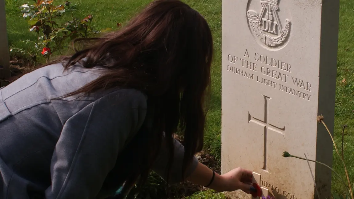 A student from King James I Academy lays a poppy on the grave of an unknown Durham solider