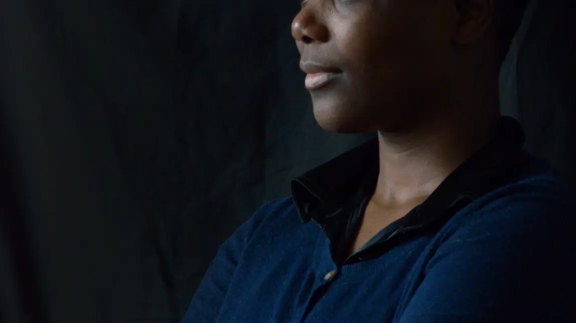 A woman in blue top against a black background