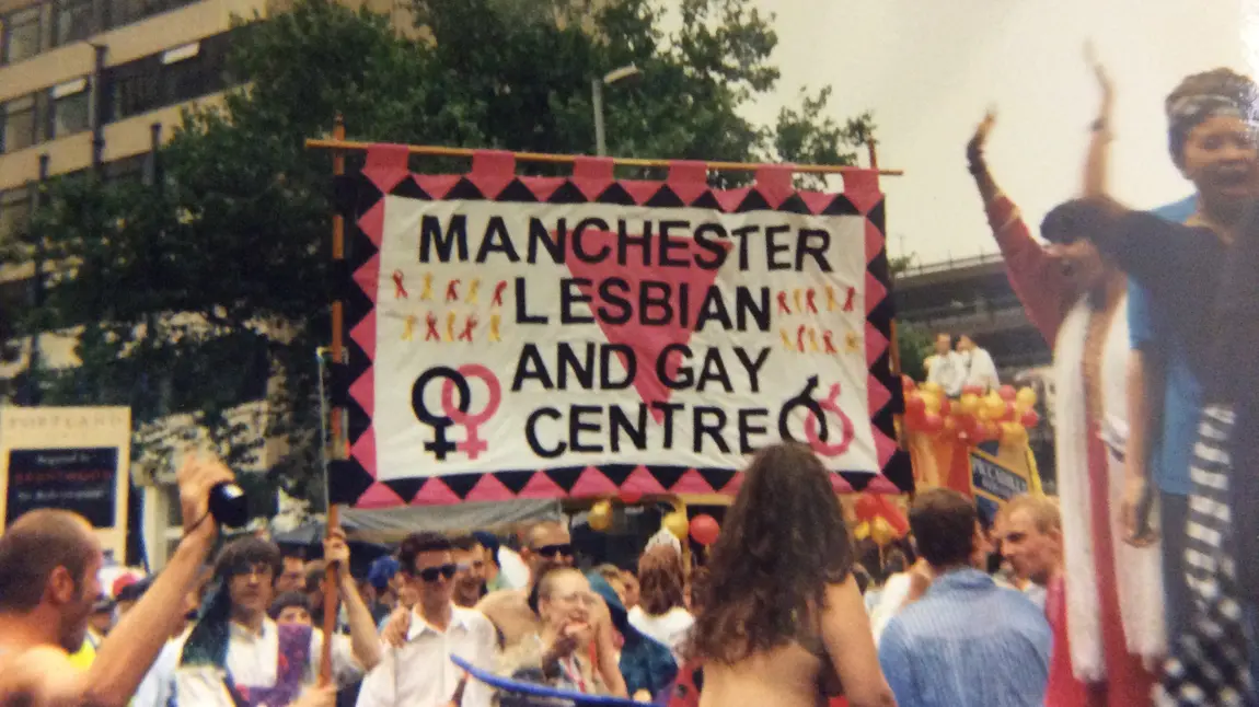 A crowd carrying a Manchester Lesbian and Gay Centre banner