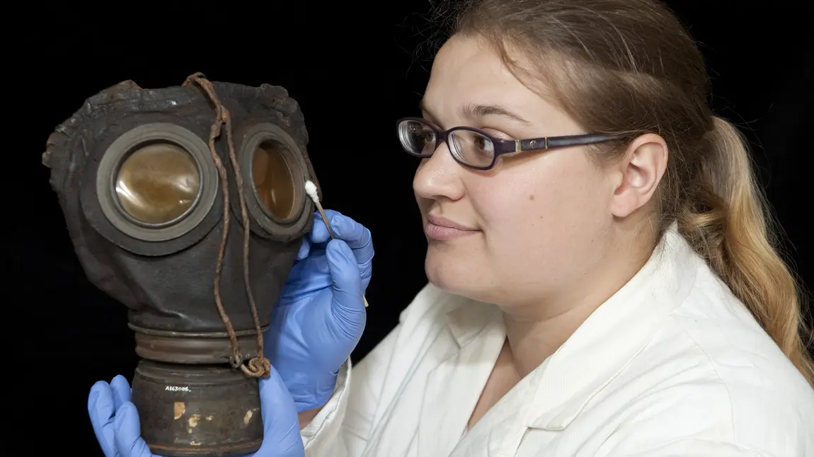 Conservation intern Louise Stewart cleaning a gas mask for the exhibition