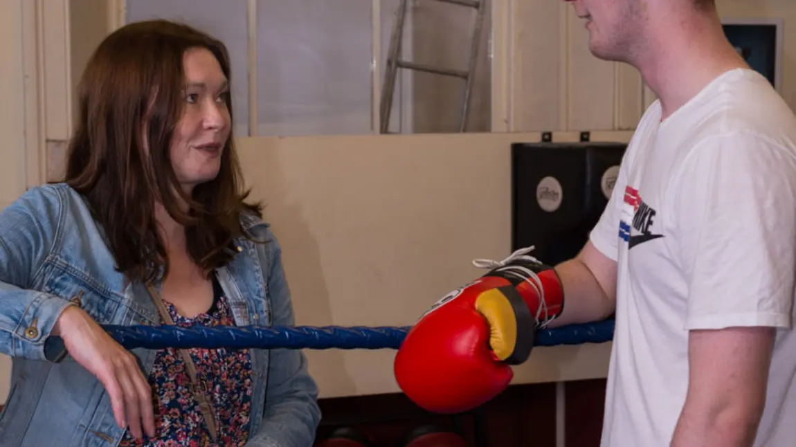 A woman talks to a young male boxer