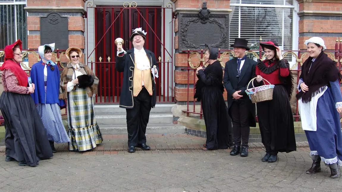 A bell ringer and other people in historic dress