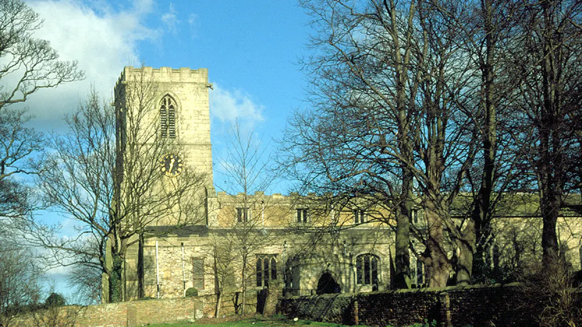 A medieval stone church with trees in front.