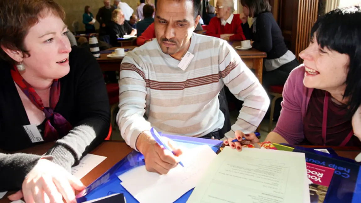 Two women and a man discussing papers