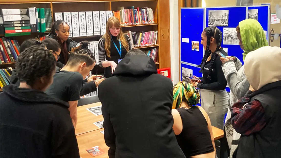 A group of people working around a table looking at research materials