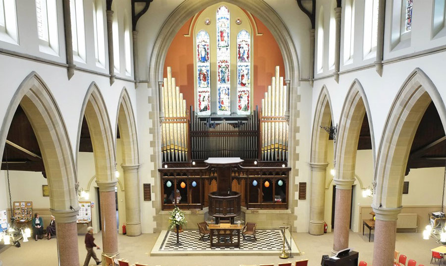 An organ on the far wall of a church, with arches on the either side